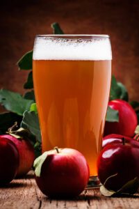 Glass of apple beer surrounded by apples