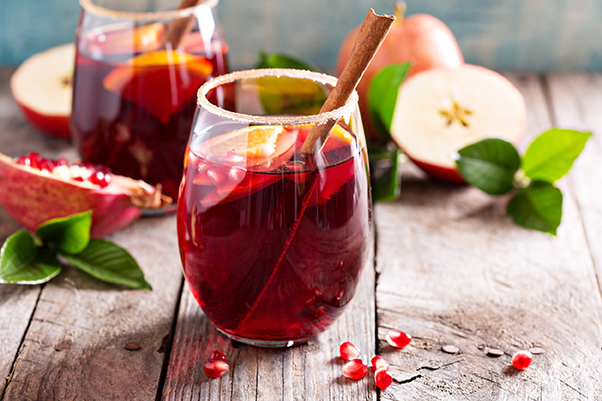 Apple beverage surrounded by apples on a wooden tabletop