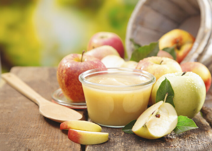 Apples, sliced apples, and apple sauce on a wooden tabletop