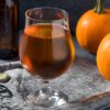 photo of a tulip snifter of porter pumpkin beer with a beer bottle, can opener, and pie pumpkins | Puree Arete photo of a tulip snifter of porter pumpkin beer with a beer bottle, can opener, and pie pumpkins