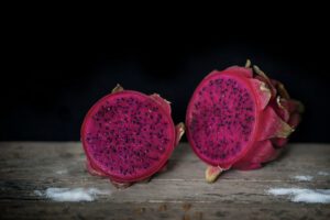 photo of Red Dragon fruit on wooden surface solid black background still life shooting style